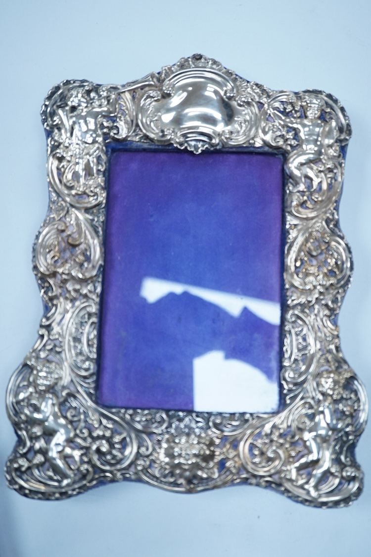 An Edwardian repousse silver mounted photograph frame, by Synyer & Beddoes, Birmingham, 1901, 23.4cm, together with a George V plain silver rectangular photograph frame, with ribbon bow crest, Stuart Clifford & Co, Londo